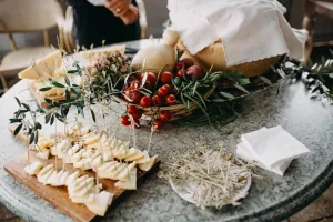 Upieczony batat przekrojony na pół z ziołami i oliwą na talerzu, w tle miska z całymi batatami na kuchennym stole.